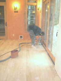 Lots of sawdust in the air as worker sands the maple floor in the dining area